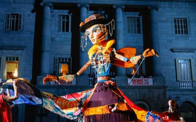 A giant bee puppet at nightime in Barcelona with a ribbon skirt held out in a twirl