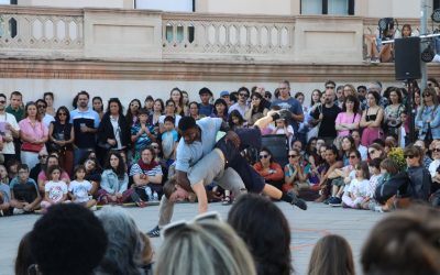 Two dancers perform an acrobatic move in front of a crowd of people.