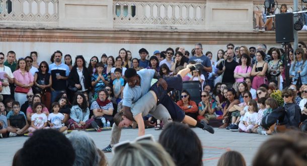 Two dancers perform an acrobatic move in front of a crowd of people.