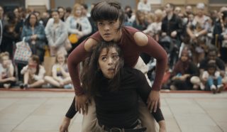 Two female dancers balancing on each others backs in an outdoor performance