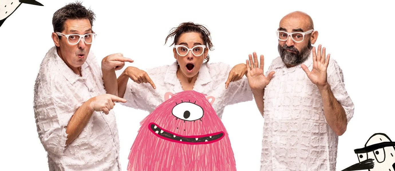 Three adults in white textured shirts and white glasses look surprised and point at a pink, one-eyed cartoon monster with a big smile, standing in front of them against a white background.